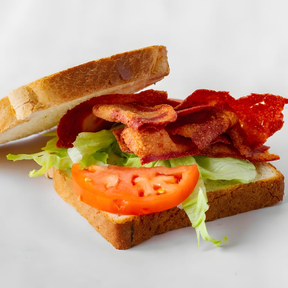 A bacon, lettuce, and tomato sandwich on toasted white bread, with crispy bacon slices.