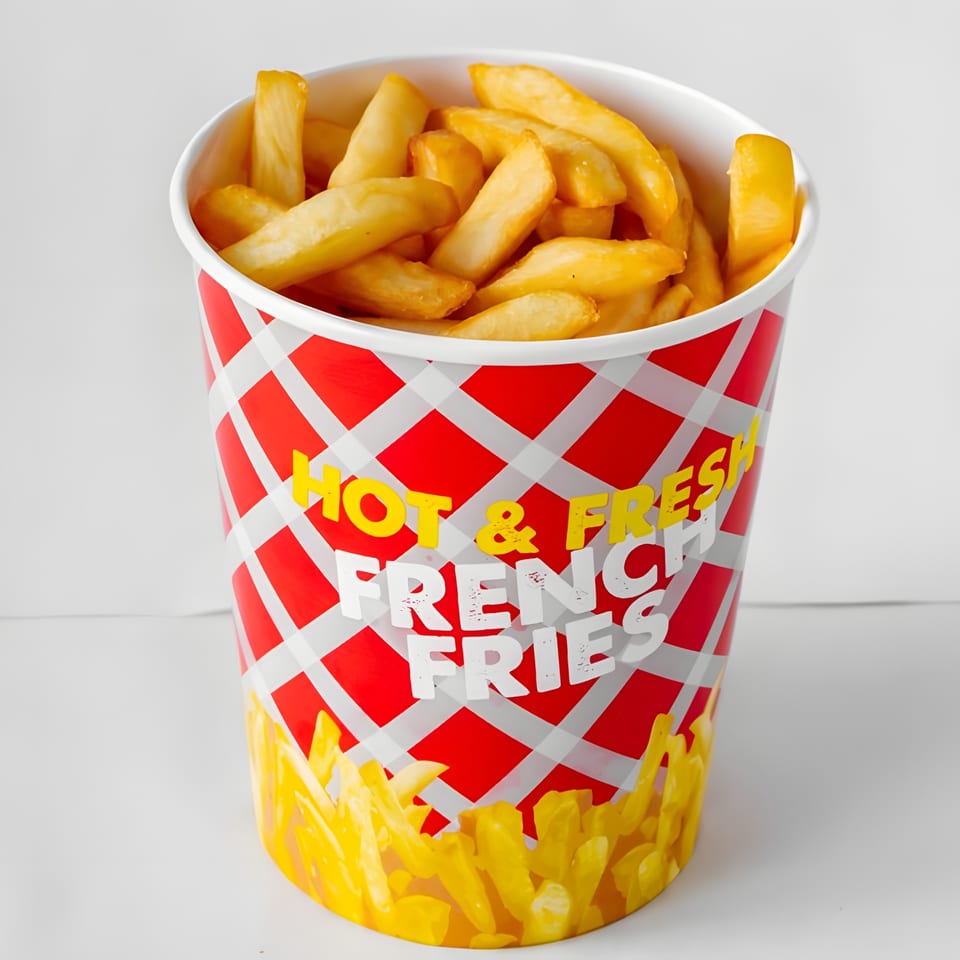 A red and white checkered cup overflowing with golden, crispy French fries.
