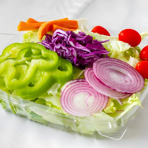 Fresh garden salad with lettuce, green peppers, red cabbage, red onions, carrots, and cherry tomatoes.