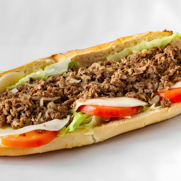 A Soprano's Pizza cheesesteak hoagie with steak, cheese, lettuce, and tomatoes on a white background.